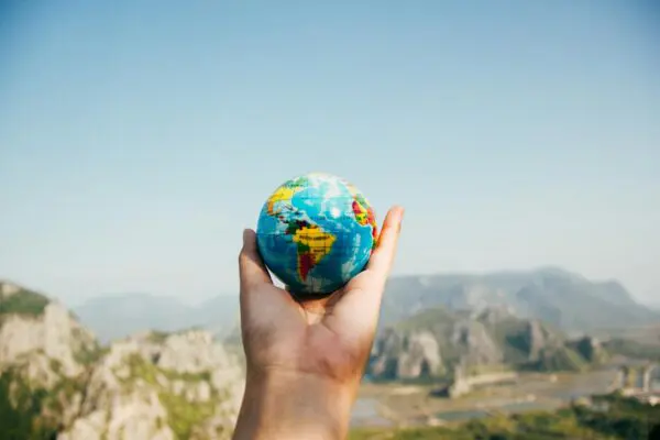 April 22nd: Earth Day, in a Nutshell Person Holding World Globe Facing Mountain