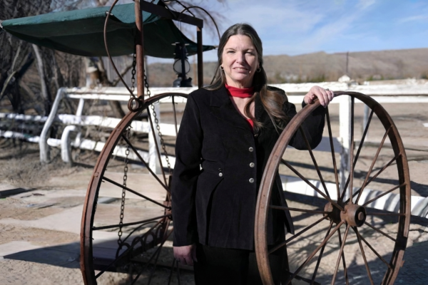 Tammy Holt-Still standing next to an antique wagon wheel