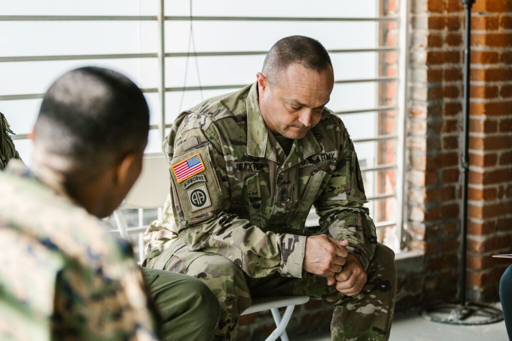 A therapy session focusing on mental health support among military veterans. Photo by RDNE Stock project from Pexels: https://www.pexels.com/photo/photo-of-a-distressed-soldier-7467909/